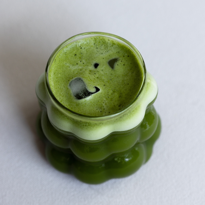 Iced Matcha in a grape shaped glass cup, creamy micro foam.