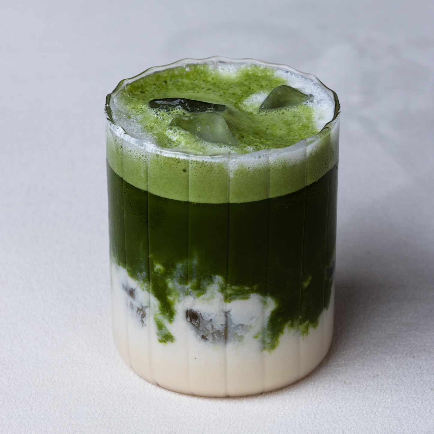 Matcha Energy Iced Latte drink with ice cubes in a glass.