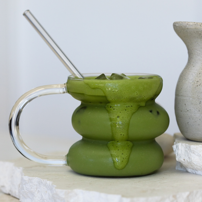Matcha Energy in a unique mug with a handle and straw, placed on a light surface.